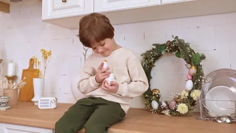 A boy sits at kitchen of rustic style and hugs little yellow duckling Stock Footage 263830892