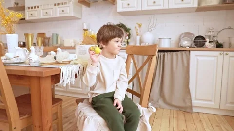 A boy sits at kitchen of rustic style in Easter decorations Stock Footage 263844615