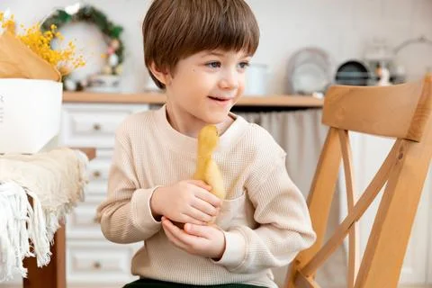 A boy sits at kitchen of rustic style and hugs little yellow duckling Stock Photos