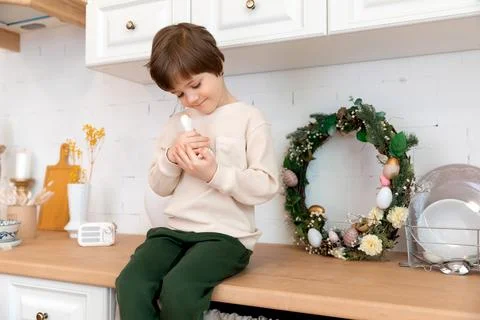 A boy sits at kitchen of rustic style with Easter decorations Stock Photos