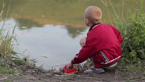 Boy sits on the lake Stock Footage 75777173