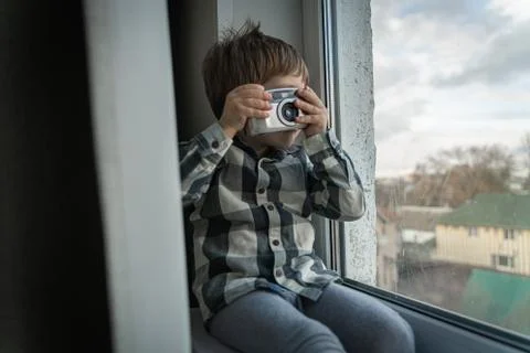 Boy sits near the window and takes pictures of dad Stock Photos