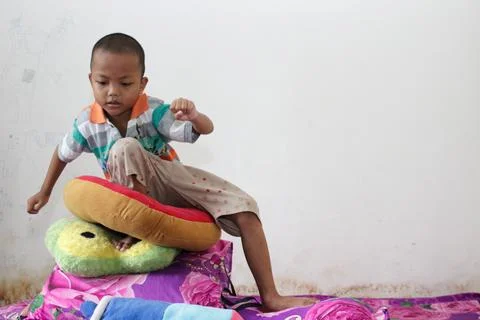 A boy sits playing on the bed Foto stock
