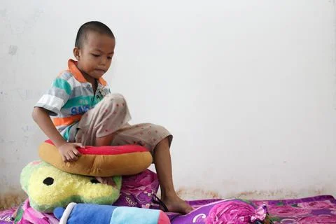 A boy sits playing on the bed Stock-Fotos