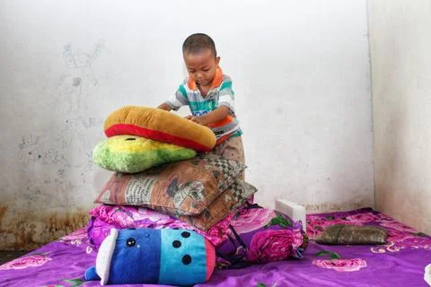A boy sits playing on the bed Stockfoto's