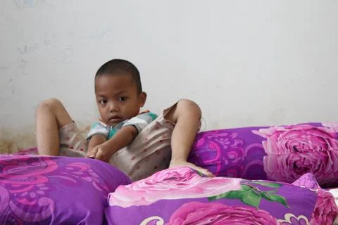 A boy sits playing on the bed Foto stock