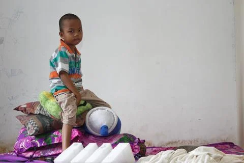 A boy sits playing on the bed Photos