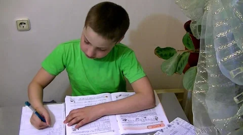 Boy sits at the table and does his homework Stock Footage 62475703