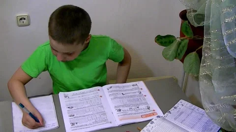 Boy sits at the table and does his homework Stock Footage 62475815