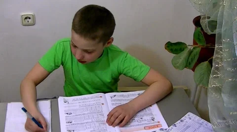 Boy sits at the table and does his homework 库存影片 62475835