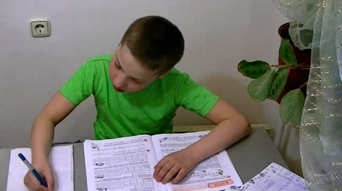 Boy sits at the table and does his homework Stock Footage 62475965