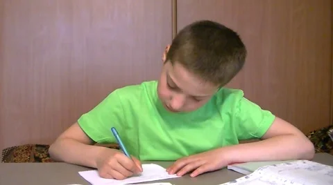 Boy sits at the table and does his homework Stock Footage 63228456