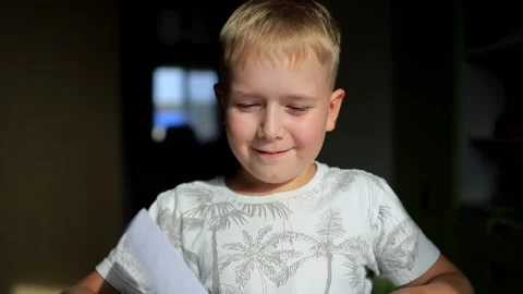 The boy sits at the table and flips through the notebook Stock Footage 130909838
