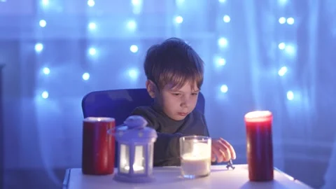 A boy sits at a table with candles Stock Footage 312610673