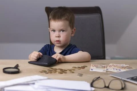 The boy sits at a table with money Фото
