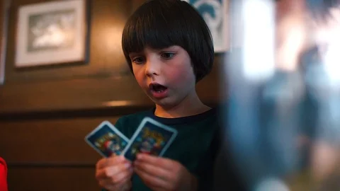 A boy sits at a table puts cards on a table in a board game Stock Footage 118526433
