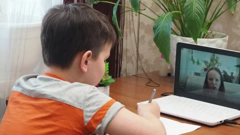 A  boy sits at the table writing homework notebook computer to study School 库存影片 158456653