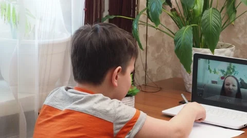 A  boy sits at the table writing homework notebook computer to study School Stock Footage 158458468