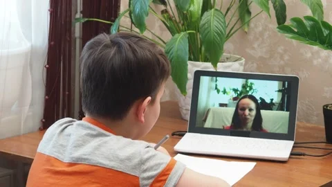 A  boy sits at the table writing homework notebook computer to study School 库存影片 158461867