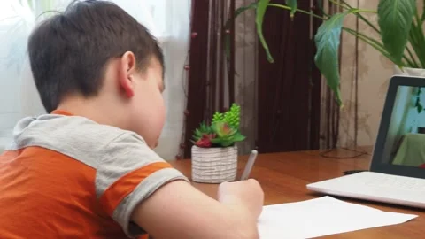 A  boy sits at the table writing homework notebook computer to study School 库存影片 158463027