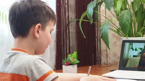 A  boy sits at the table writing homework notebook computer to study School 库存影片 158464015