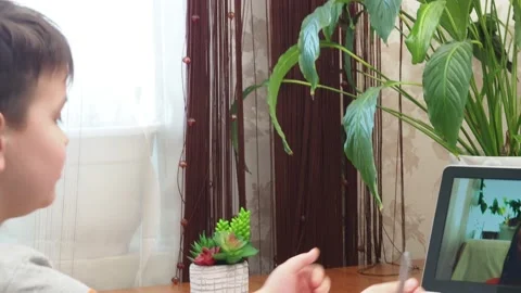 A  boy sits at the table writing homework notebook computer to study School 库存影片 158464927