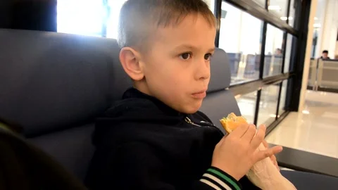 A boy sits at a train station or aroport while waiting for a train or plane 库存影片 143611572