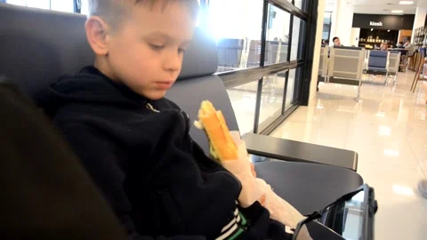 A boy sits at a train station or aroport while waiting for a train or plane Stock Footage 143611652