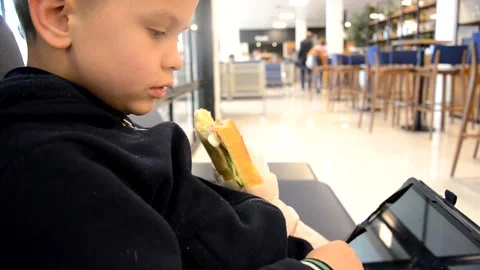 A boy sits at a train station or aroport while waiting for a train or plane 库存影片 143611672
