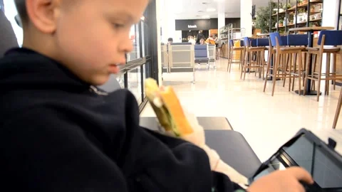A boy sits at a train station or aroport while waiting for a train or plane 库存影片 143611679