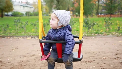 Boy sitting and smiling in on the swing Stock Footage 142306429