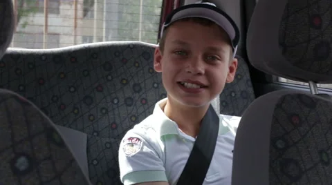 Boy sitting on the back seat of a car wearing a seat belt Stock Footage 64952977