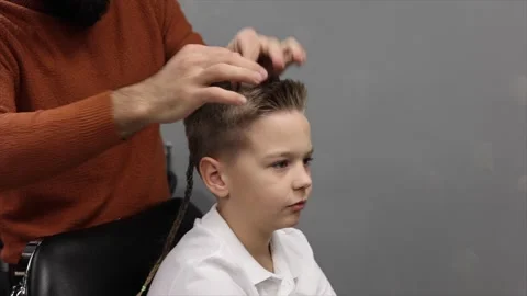 A boy is sitting in a Barber's chair while his hair is being done, a barbershop Stock Footage 146663743