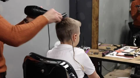 A boy is sitting in a Barber's chair while his hair is being done, a barbershop Stock Footage 146679371