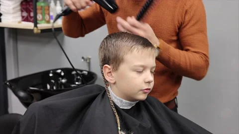 A boy is sitting in a Barber's chair while his hair is being done, a barbershop Stock Footage 146688640