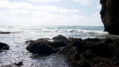 Boy sitting on beach rocks, pan shot Stock Footage 112237671