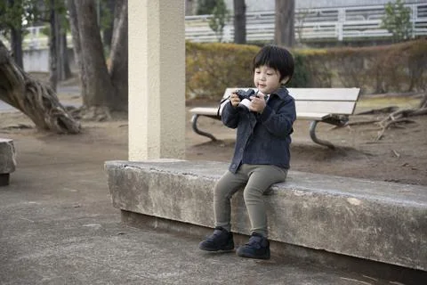 A boy sitting on a bench and checking the data taken Stock Photos