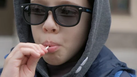 Boy sitting on a bench and eats Lollipop. Rejoices licks the candy, fools around Stock Footage 130117916
