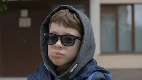 Boy sitting on a bench and eats Lollipop. Rejoices licks the candy, fools around Stock Footage 130118003