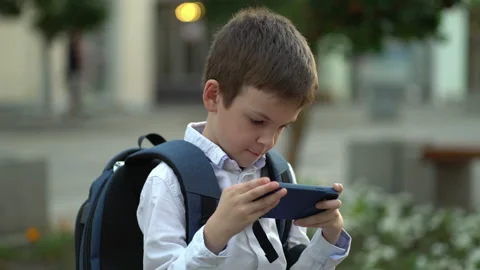 The boy is sitting on a bench with a backpack on his back and enjoying time with Stock Footage 204883123