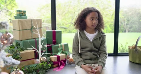 Boy sitting on bench by window, noticing tree ornaments and shifting gaze while Stock Footage 337399872