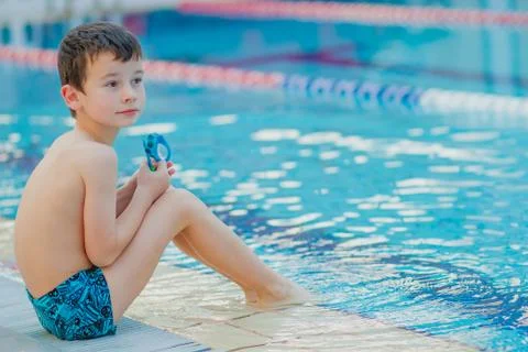 A boy is sitting on border of pool Stock Photos