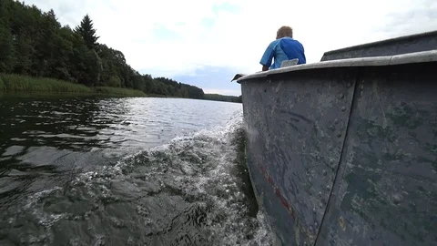 Boy sitting on the bow of a floating motor boat Stock Footage 114003588