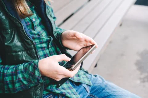 A boy is sitting on the bus stop bench with a broken phone in his hands Stock Photos