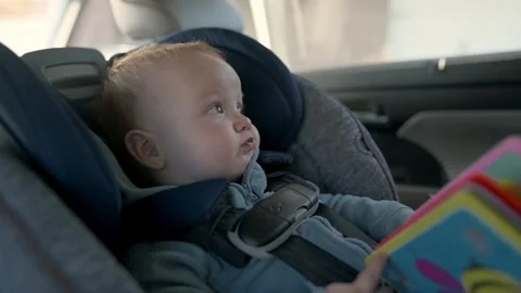 The boy is sitting in the car seat, looking out the window, smiling, travelin Stock Footage 271319082