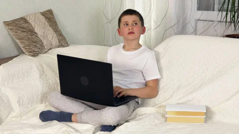 Boy sitting on comfy sofa and doing homework in apartment Stock Footage 154231905