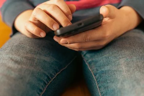 Boy is sitting on the couch and using a smartphone Stock Photos