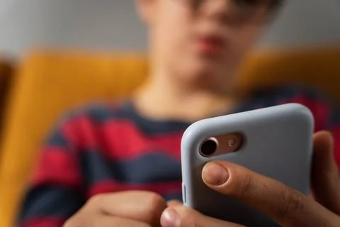 Boy is sitting on the couch and using a smartphone Foto stock