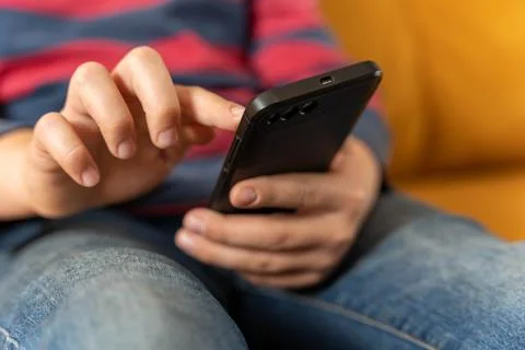 Boy is sitting on the couch and using a smartphone Stock Photos