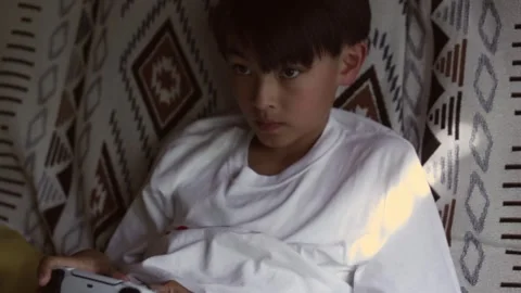 Boy sitting on a couch playing video games Stock Footage 244771673